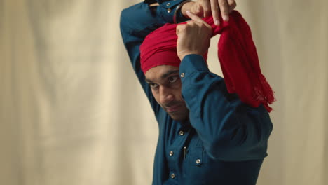 fotografía de estudio de cerca de un anciano sikh con barba atando tela para el turbante contra un fondo plano tomada en tiempo real 3