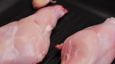 roasted rabbit legs in a grill pan, healthy diet meat close up, chef cooking rabbit on kitchen restaurant, black background. top view