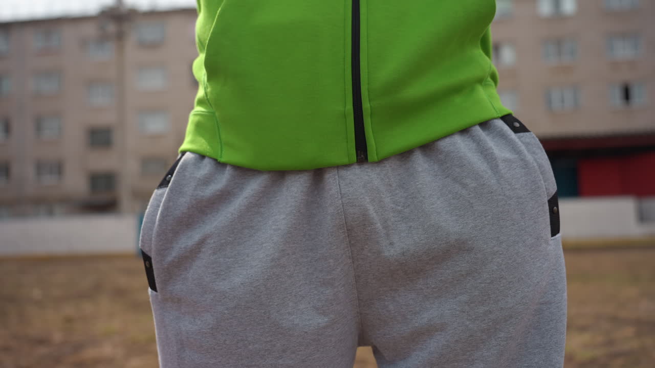 atuendo informal para exteriores, pantalones de chándal cómodos en un entorno al aire libre, persona con pantalones de chándal relajados preparándose al aire libre, persona con pantalones de chándal grises informales en un ambiente tranquilo al aire libre