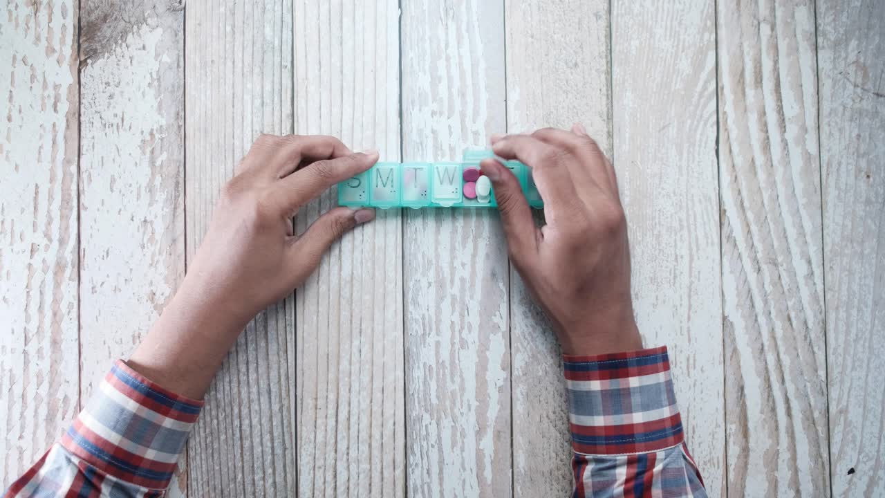Person using a weekly pill organizer