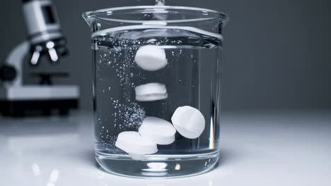 pills dissolving in water in a beaker