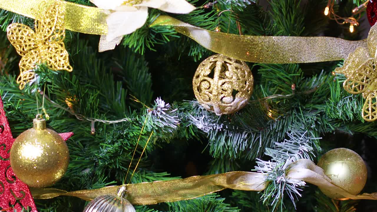 árbol de navidad decorado con adornos dorados y rojos y luces parpadeantes