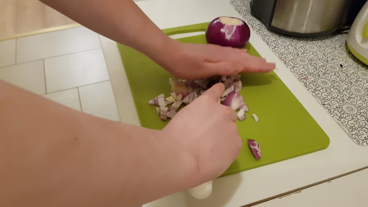 Caucasian woman cooking and cutting up purple onion