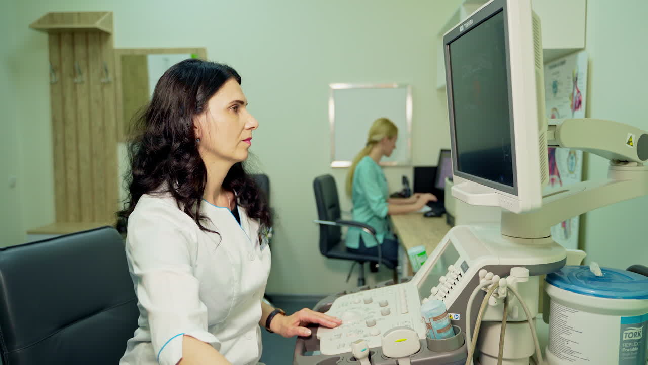 Woman doctor makes uzi. Medical specialist working on a computer while doing ultrasound diagnostic in clinic. Modern medical equipment in medicine.