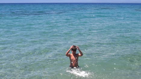 caucasian, greek boy playing in clear sea waters of kalamata, greece, peloponnese