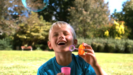 cheerful young boy blowing into a bubble wand