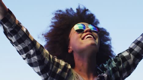 african american woman wearing sunglasses holding lbgt flag up in the air