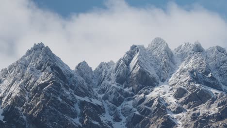 montañas escarpadas nevadas con hermosas nubes rodando sobre un cielo azul