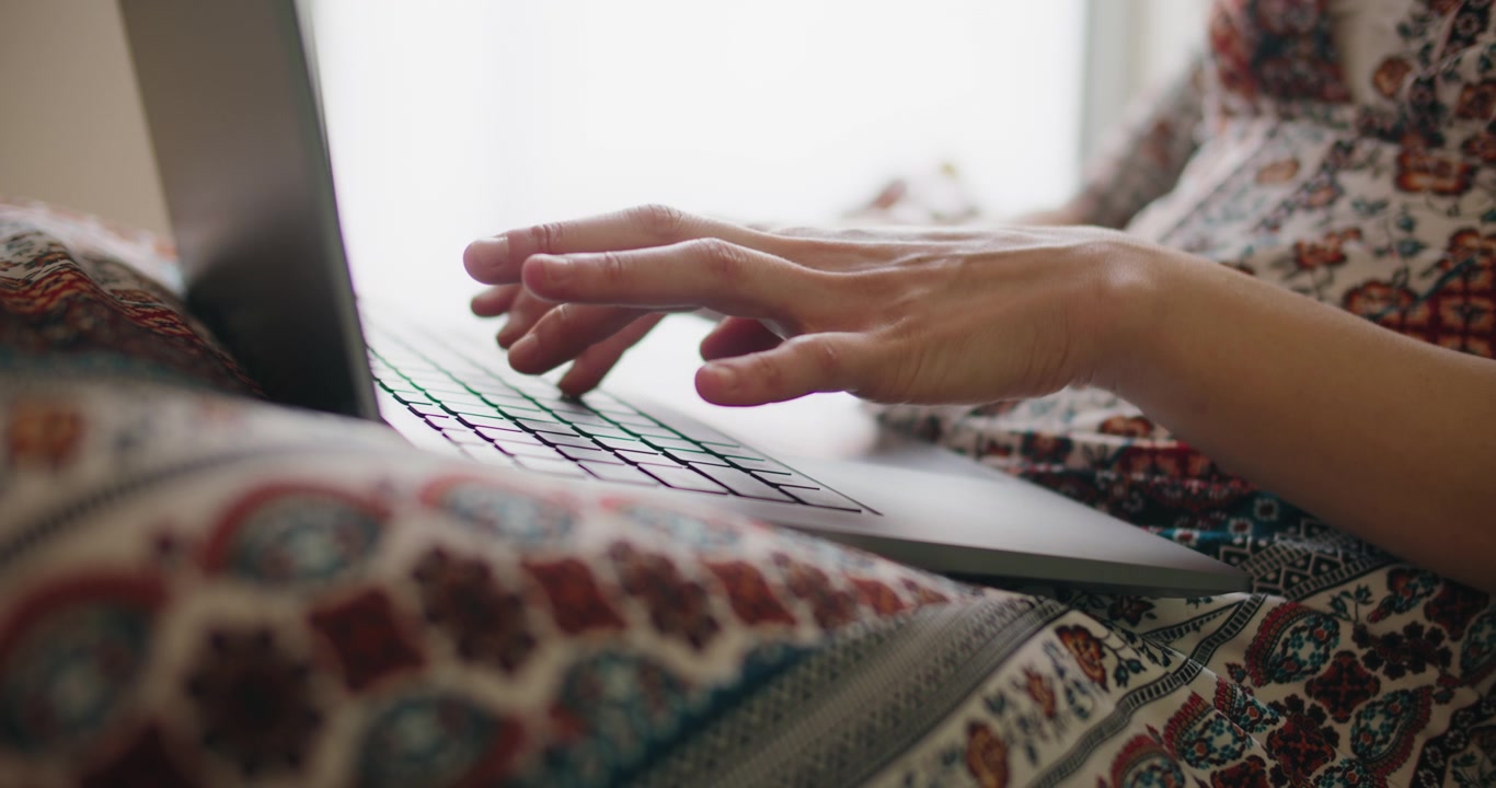 Frau tippt am Laptop-Computer, während sie zu Hause sitzt