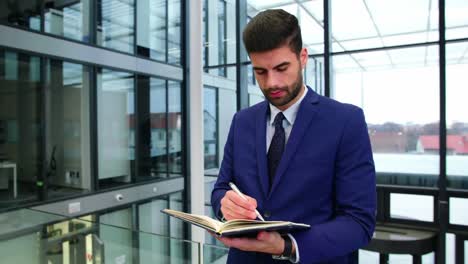 un hombre de negocios escribiendo en un diario en la oficina.