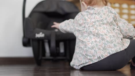 little baby girl playing with her stroller seat
