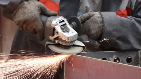 the grinder works at a metalwork factory and grinds metal parts with sparks