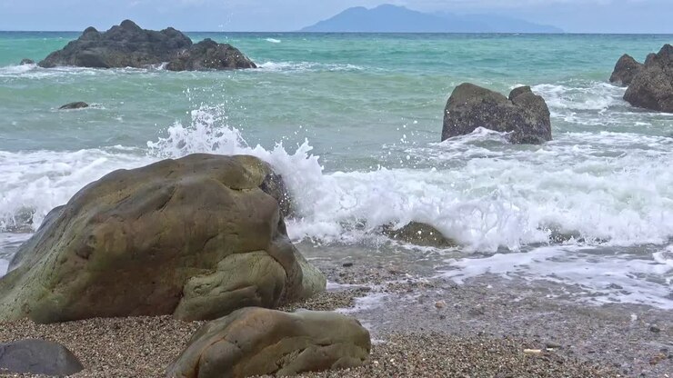 Ripresa dal basso di onde che si infrangono sulle rocce lungo la costa di Banbanon Beach, Surigao Del Norte, Filippine, in una giornata nuvolosa