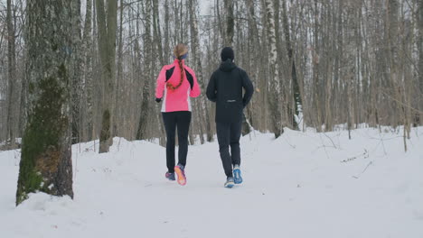 man and woman in the winter running through the park in slow motion.