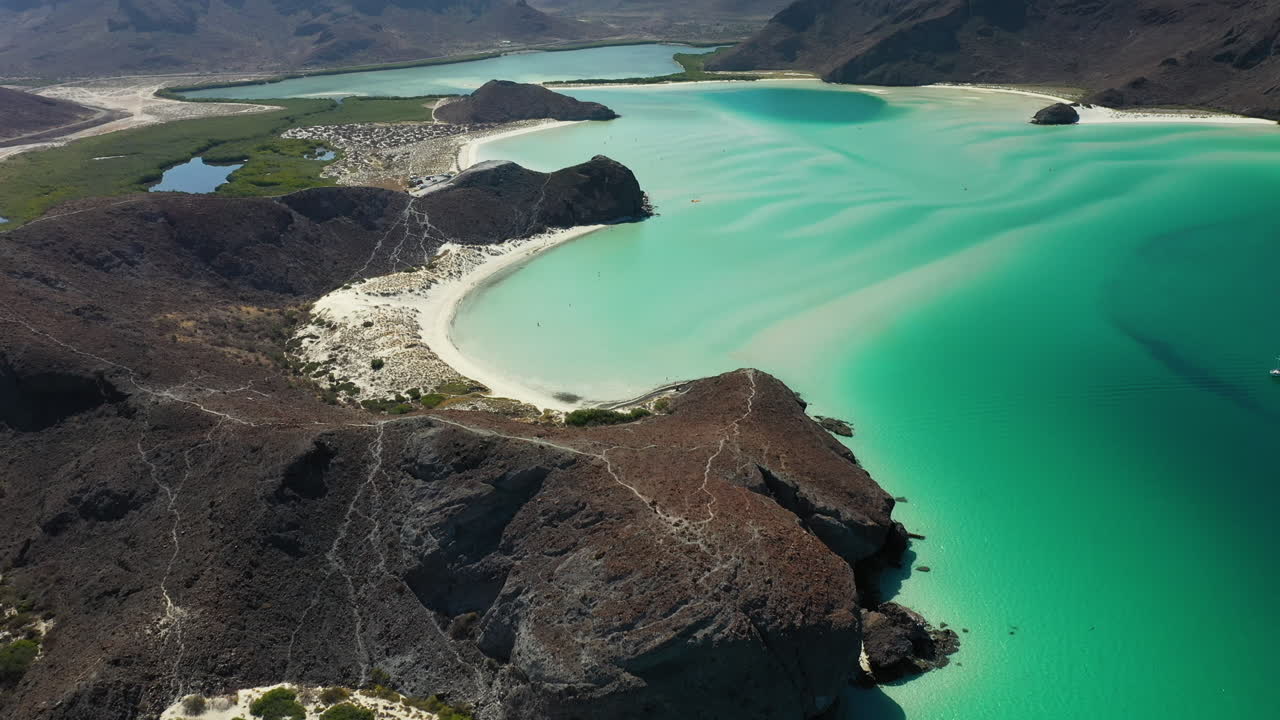 발란드라 해변의 영화 같은 드론 샷, 붉은 언덕과 청록색 바다 위로 기울어져