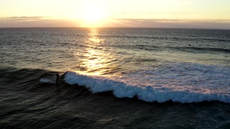 sunset drone shot of surfers catching waves on praia do guincho on cascais - sintra