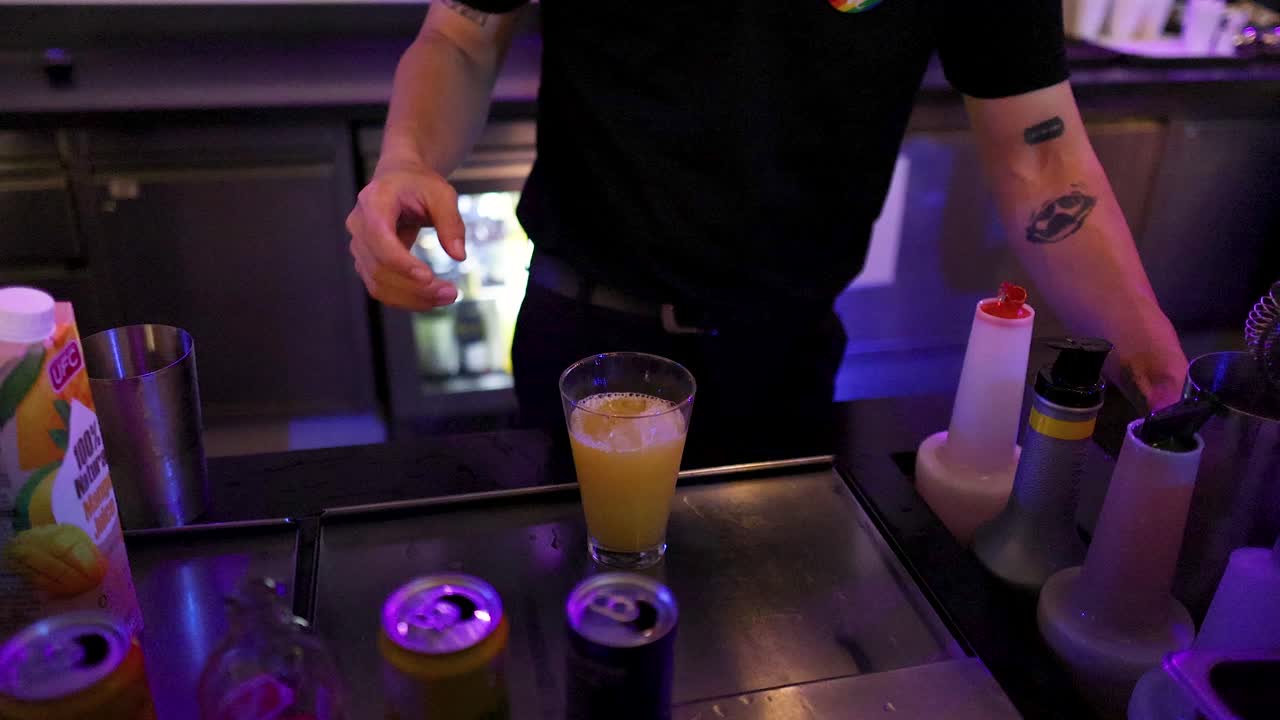 Bartender prepares cocktail with shaker and ice, neon lighting, close-up, modern bar setting