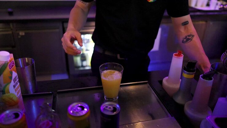 Un barman prepara un cocktail con shaker e ghiaccio, illuminazione al neon, primo piano, ambiente bar moderno