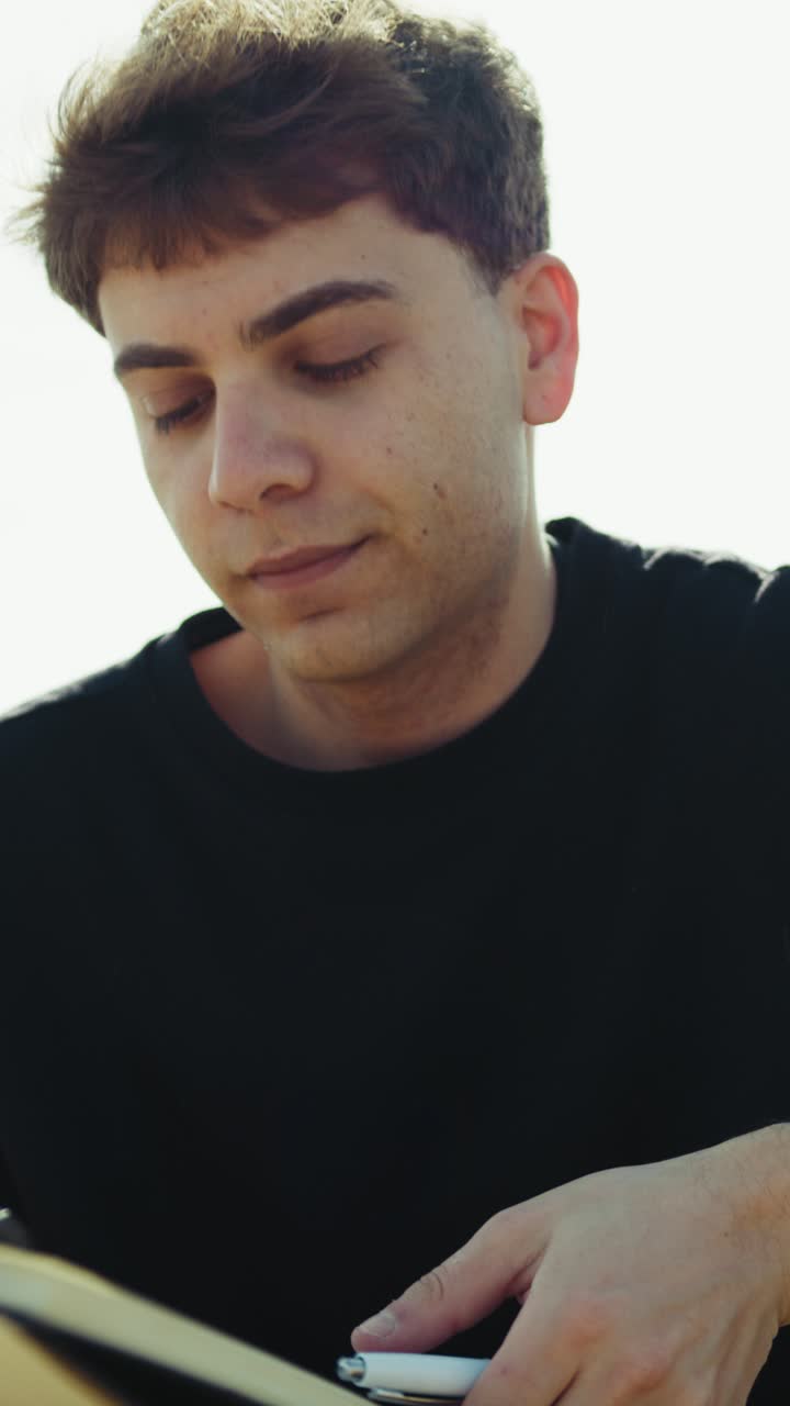 Man Writing Ideas On A Notebook With A Pen On A Park Bench