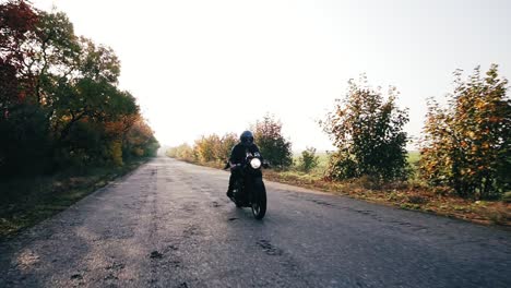 front view: man in helmet riding motorcycle on a country road