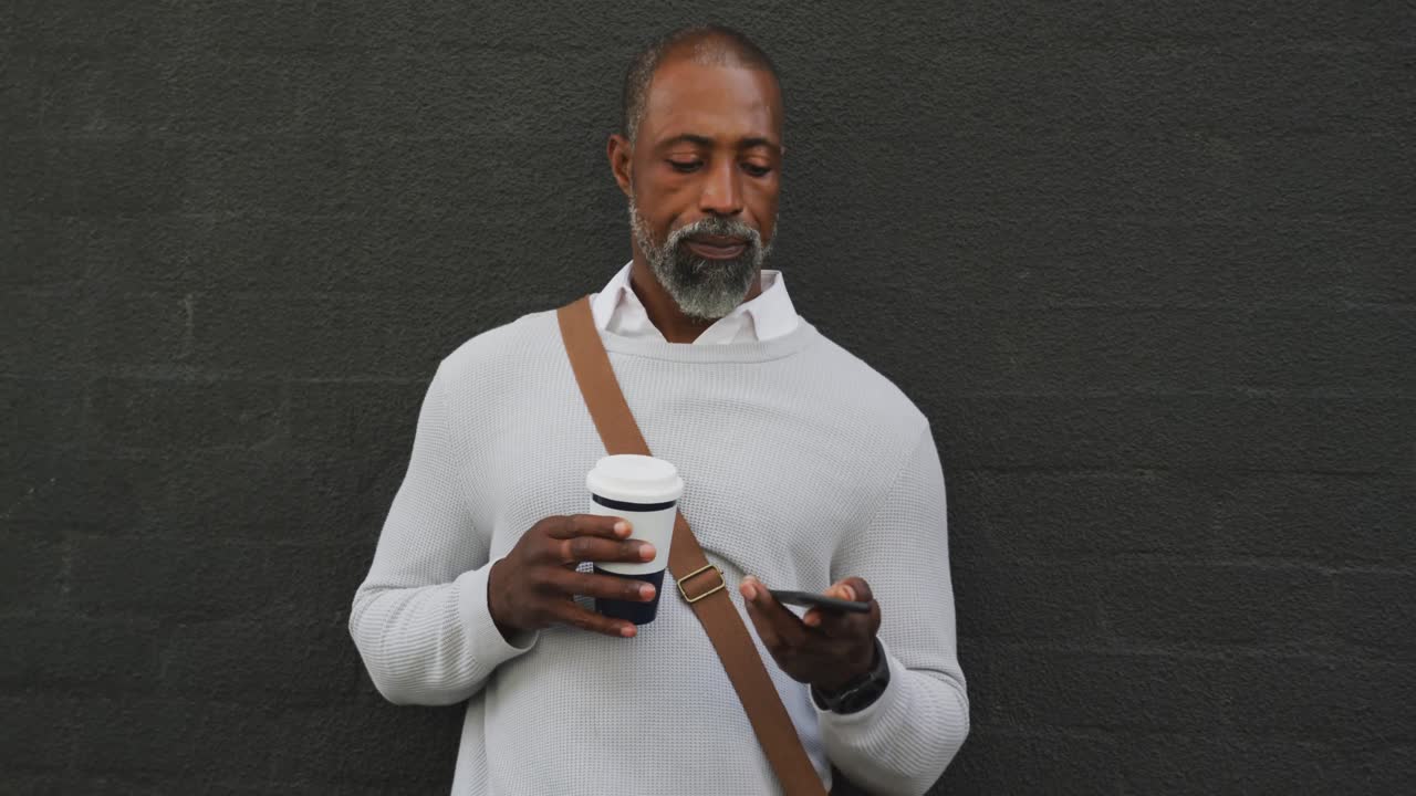 hombre afroamericano bebiendo un café y usando su teléfono