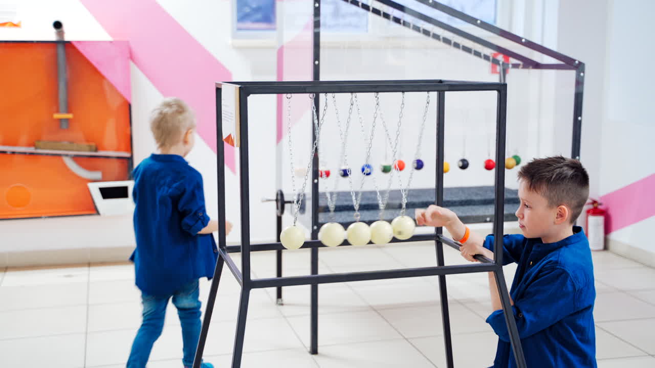 Children at the science center experimenting with Newton's cradle. The concept of physics. Museum of Science