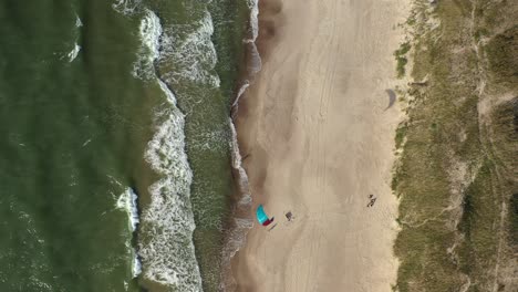 antena: vista superior de un surfista aislado con cometa de viento esperando en la playa en nida