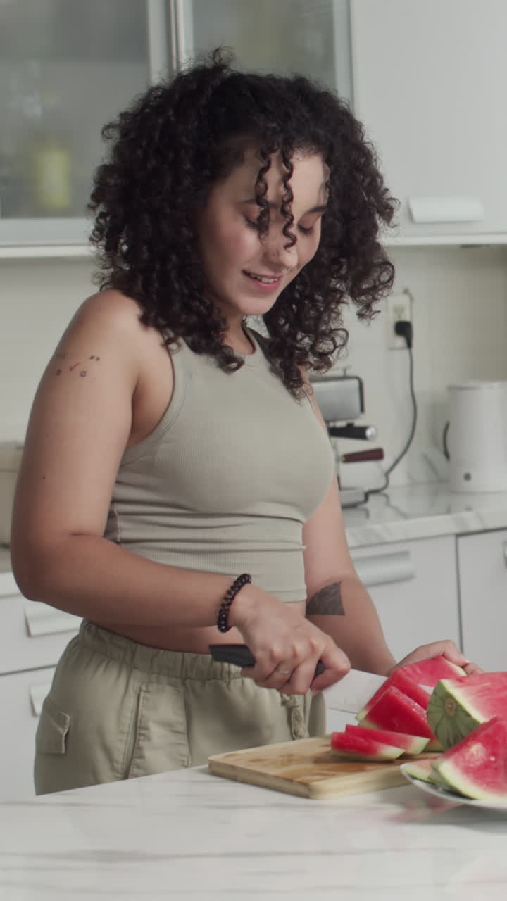 Donna che taglia l'anguria in cucina