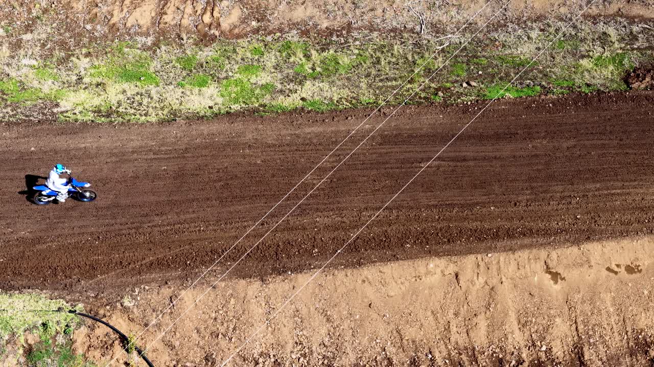 Motorbike jumps over dirt track in bushland setting