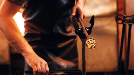 mid section of glassblower shaping a molten glass