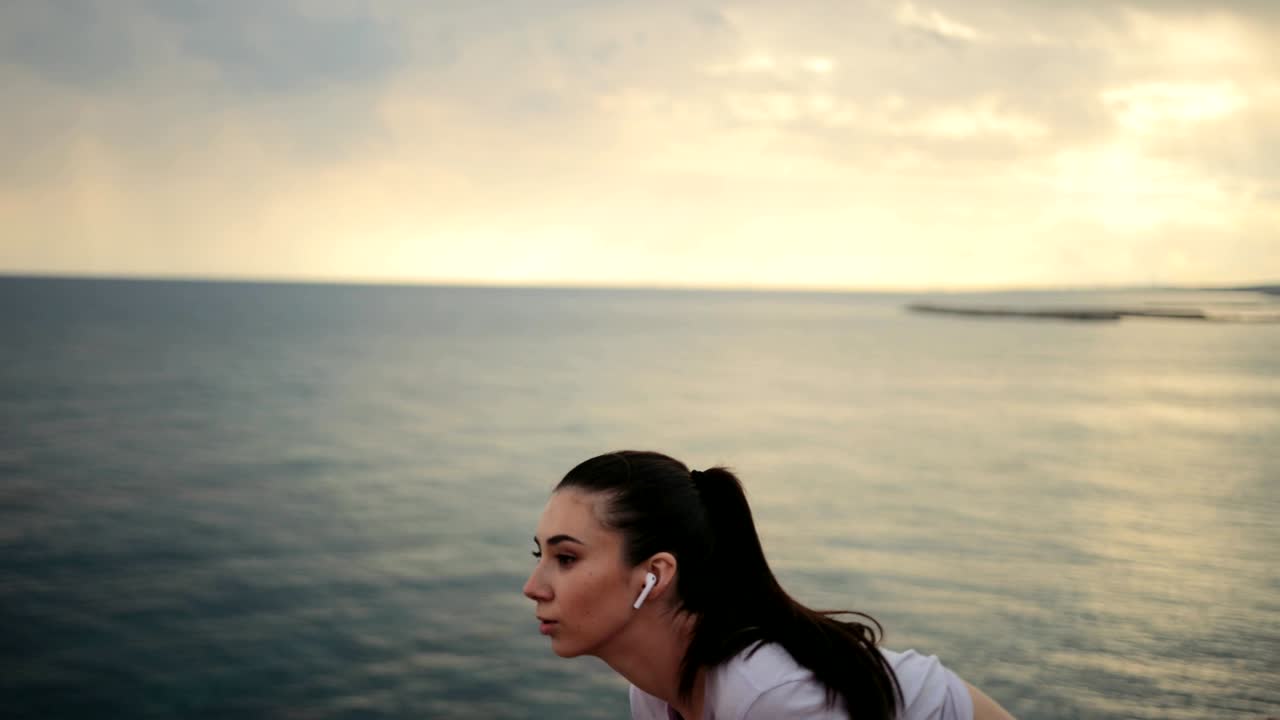mujer en forma corriendo y escuchando música junto al mar