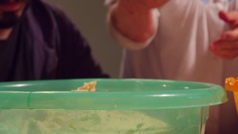 abuela tirando de la masa cruda del interior de un cuenco para cocinar pizza