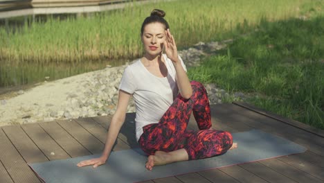 Young-woman-doing-yoga-twist-in-park