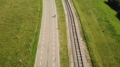 Hinter-Einem-Radfahrer,-Der-Auf-Einer-Straße-Neben-Einer-Eisenbahn-Fährt