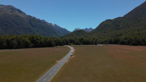 Camper-car-driving-through-beautiful-mountain-valley-in-Fiordland-Southland,-New-Zealand