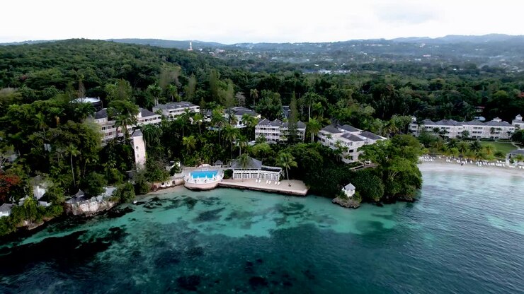 Panoramica aerea in avvicinamento su un resort in Giamaica con piscina e spiaggia.