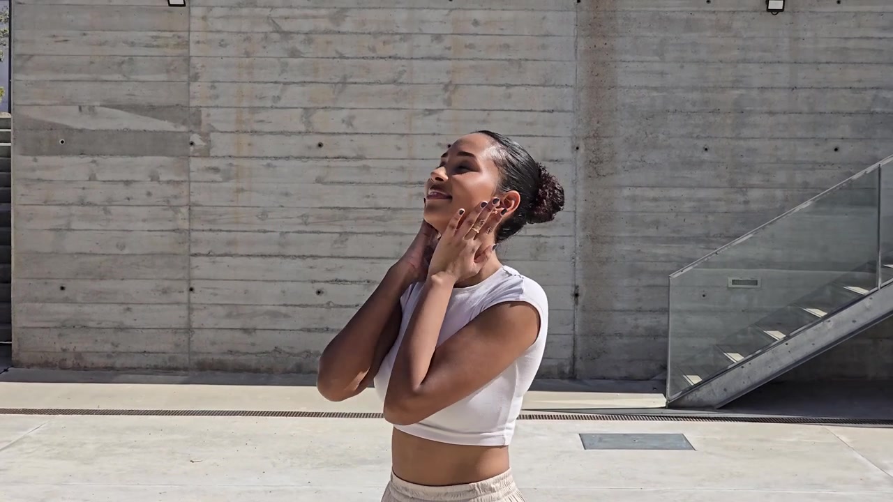 Uma mulher posando com confiança ao ar livre em um cenário arquitetônico moderno, exibindo beleza.