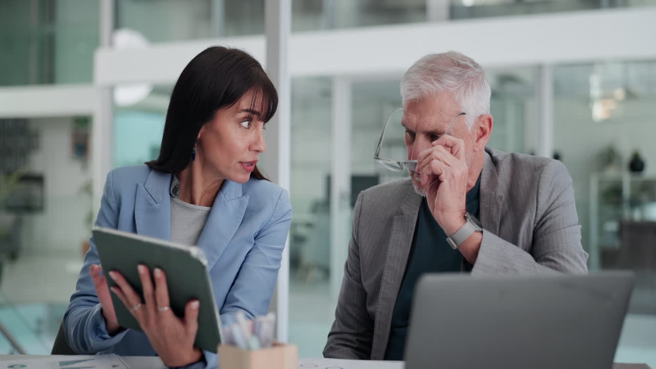 Business Colleagues Discussing Data on Tablet and Laptop in Office
