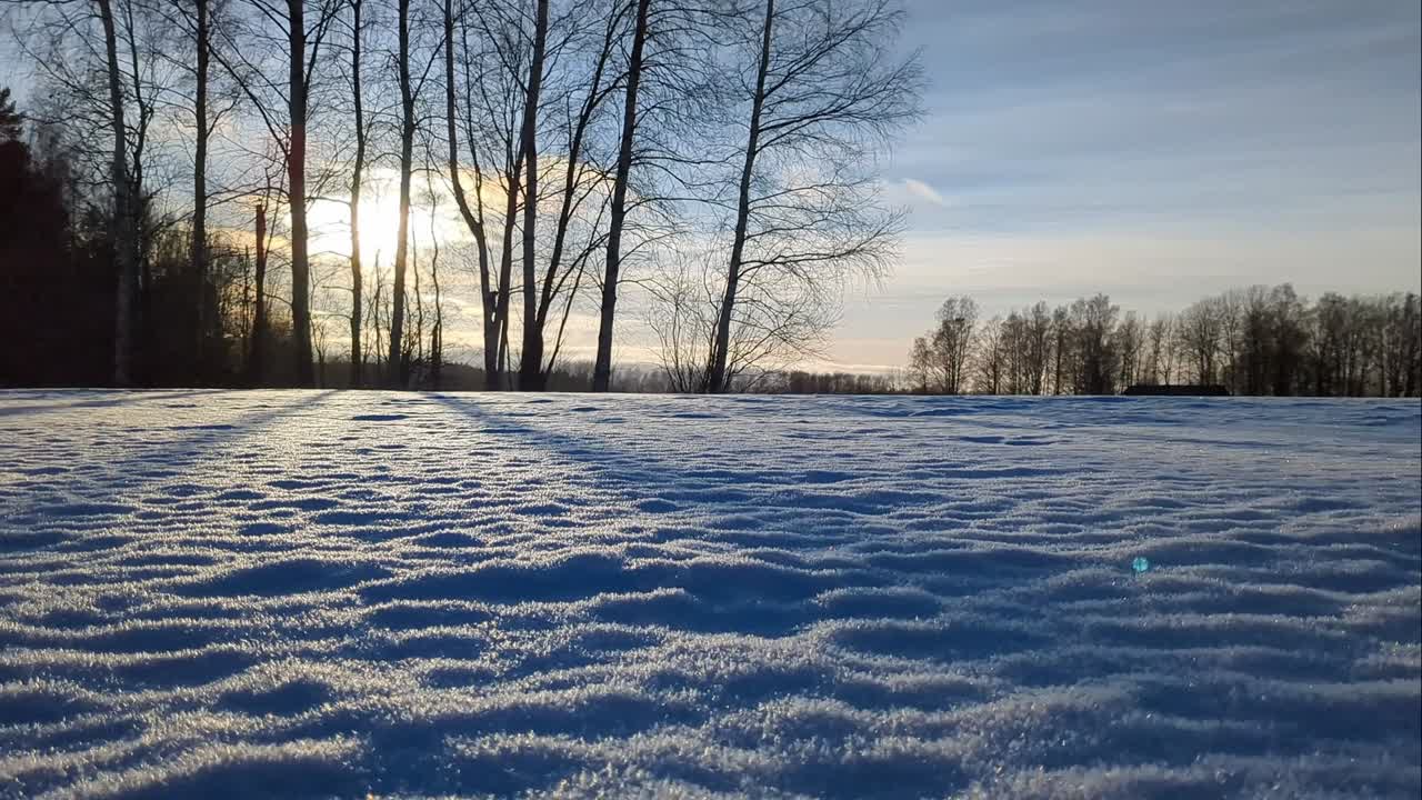 Snow covered field at sunset, snowy winter countryside scenery, backlight, moving shot