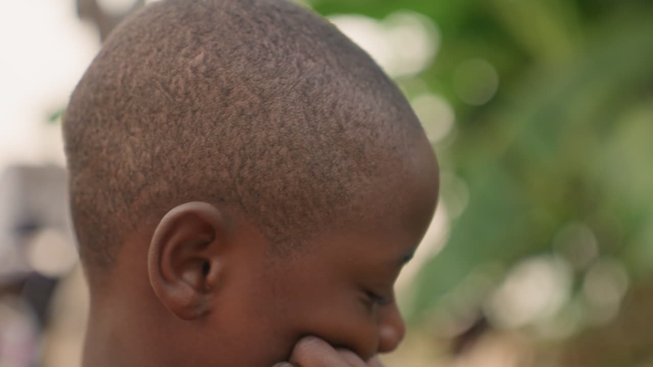 Un bambino osserva in silenzio. Un giovane osserva attentamente una vivace scena di strada. Il bambino osserva con calma la vibrante attività all'esterno. Un giovane bambino osserva una vivace scena di strada con silenziosa curiosità e attenzione.