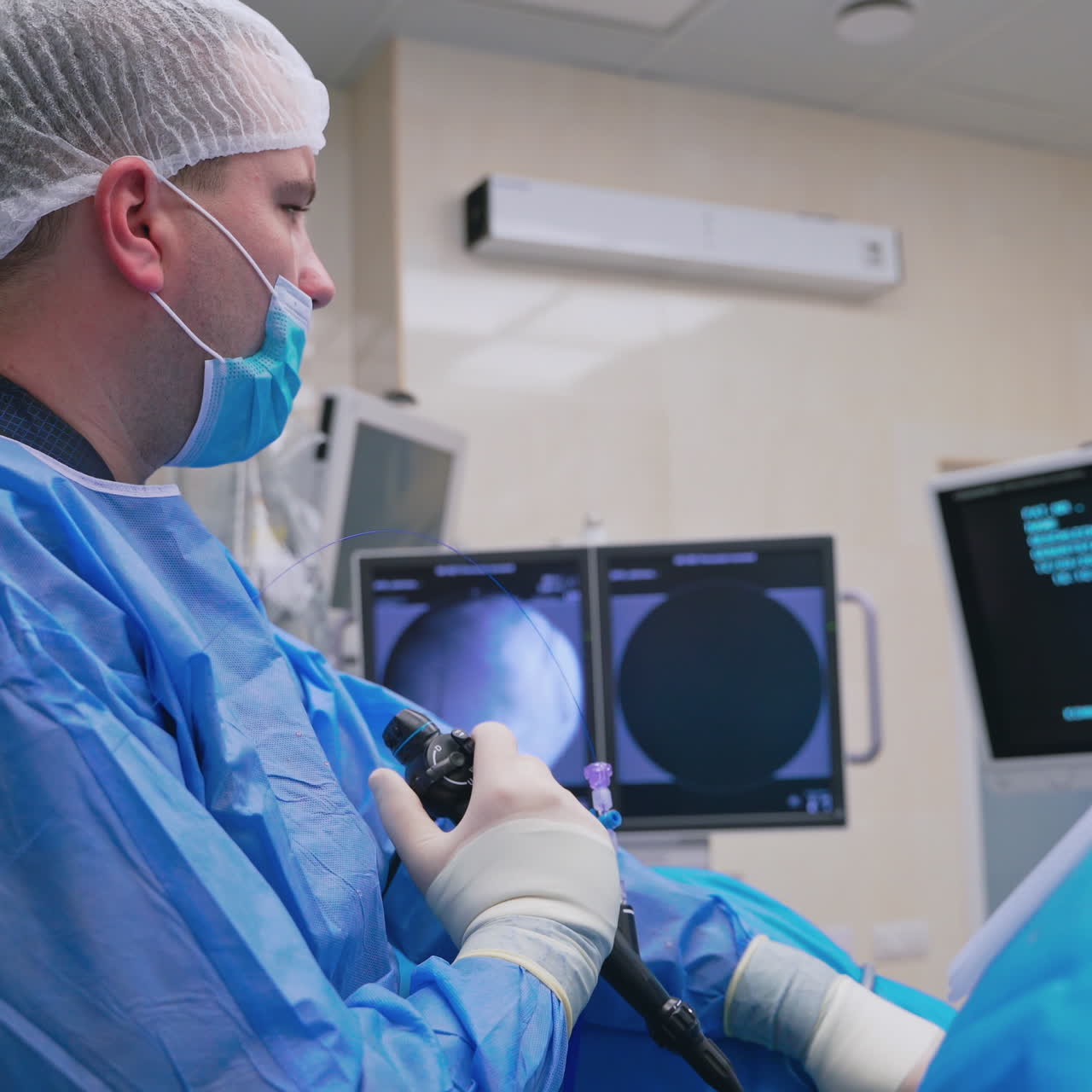 Specialist conducts laparoscopic surgery. Surgical operation with modern medical equipment in clinic. Side view of a doctor looking at the screen.