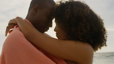 vista lateral de una pareja afroamericana envuelta en una manta en la playa 4k