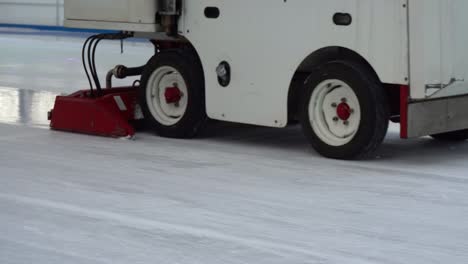 operating zamboni vehicle resurfacing ice skating and hockey rink arena, low angle tracking