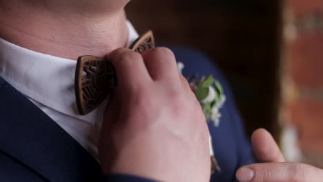 man adjusting wooden bow tie