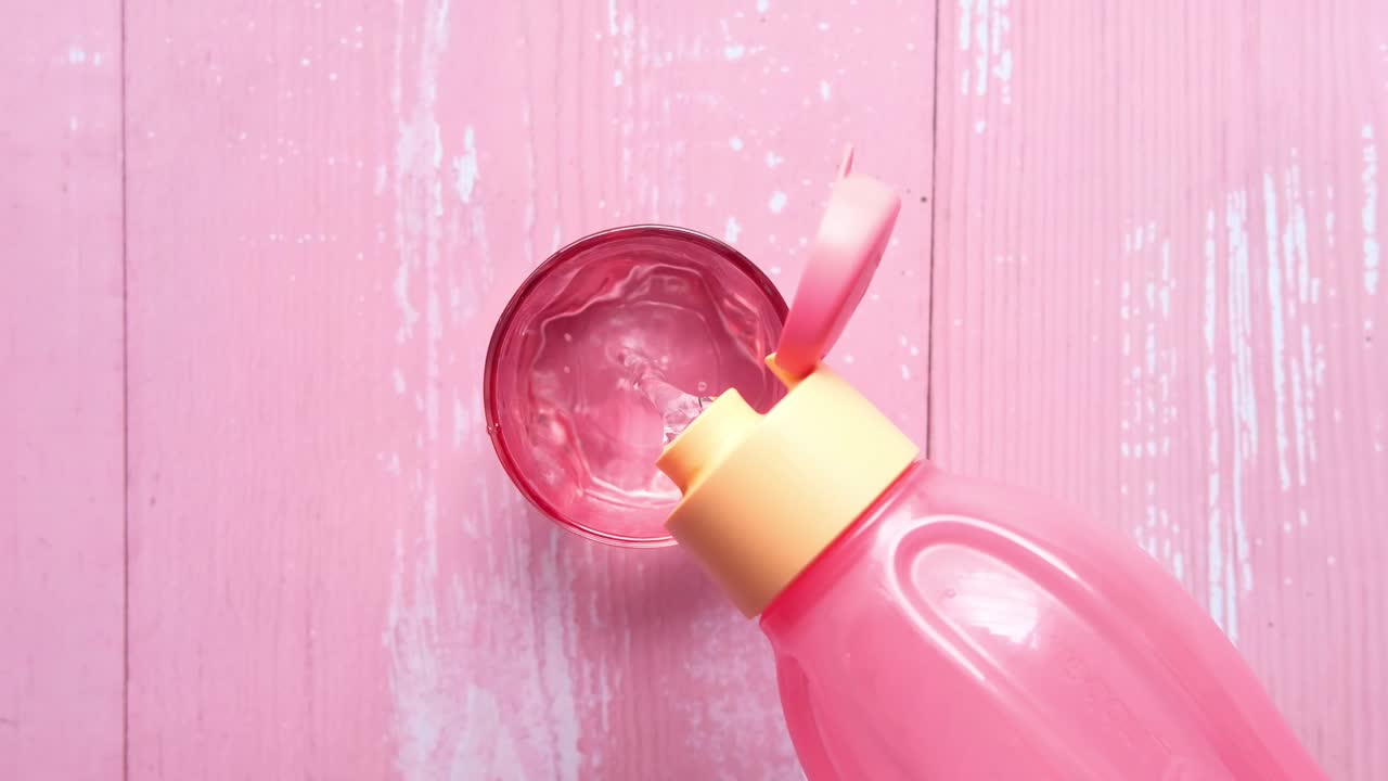 botella de agua rosa vertiendo agua en un vaso