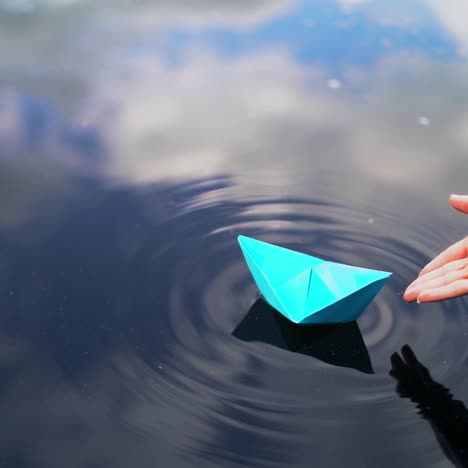 hand and paper boat in river