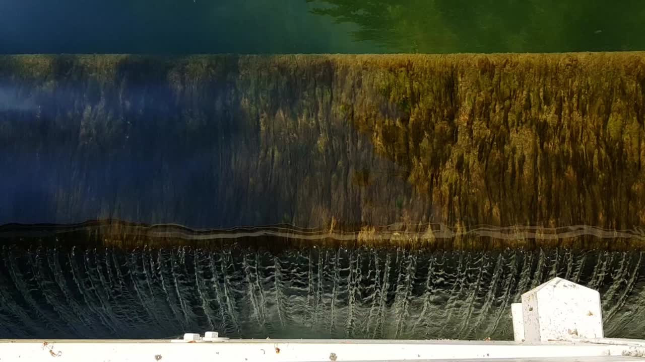 Static top view of small waterfall with algae on ground on sunny day.