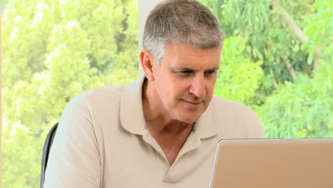 mature man working on his laptop and then posing