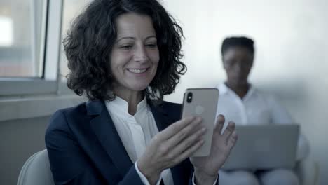 cheerful businesswoman using smartphone