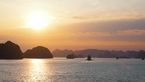 ha long bay's cruise ships glide through a mesmerizing seascape where towering limestone karsts cast dramatic silhouettes against a radiant sunrise sky
